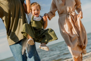 Cropped shot of happy family walking and having fun on the beach with happy cute girl