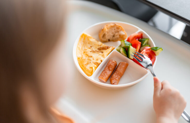 Little girl have a balanced breakfast in home kitchen in the morning